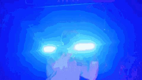 a person is standing in a dark room with blue lights coming out of their eyes .