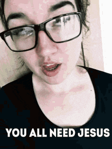 a woman wearing glasses is making a funny face and says you all need jesus .