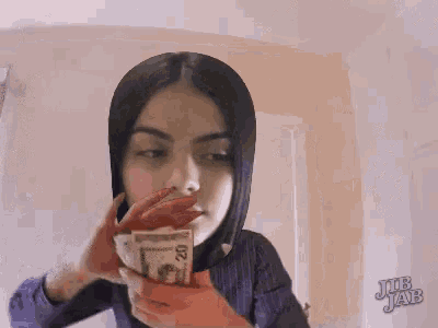 a woman is holding a bunch of money in front of her face