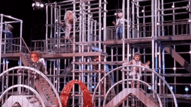 a group of people are standing on top of a roller coaster .