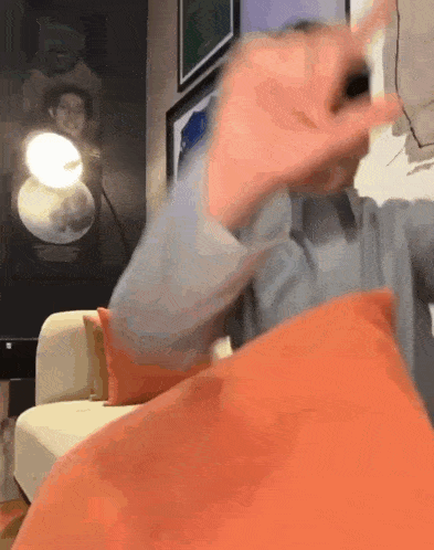 a person is sitting on a couch with a pillow in front of their face