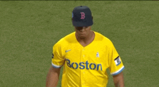 a man wearing a yellow boston jersey stands on a baseball field
