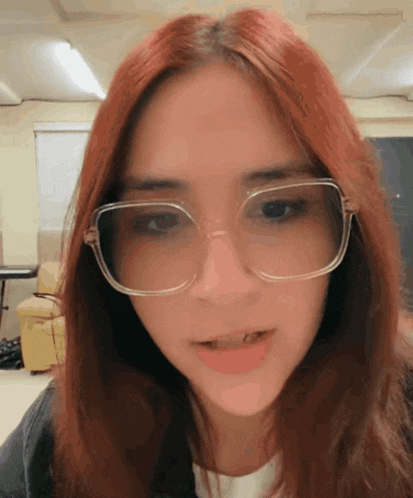 a close up of a woman wearing glasses and a white shirt