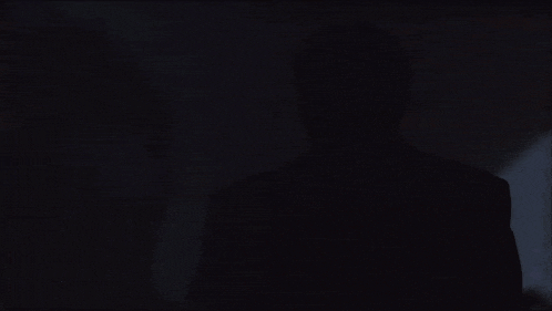 a man lighting a cigarette in a dark room