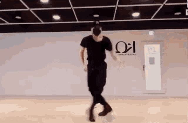 a man is dancing in a dance studio wearing a black shirt and black pants .