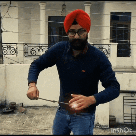 a man wearing a turban and glasses holds a stick