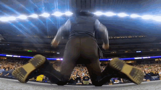 a man kneeling down in front of a crowd at a stadium with a sign that says ' champions ' on it