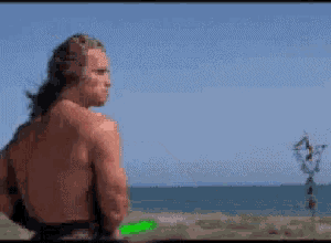 a man without a shirt is throwing a green frisbee