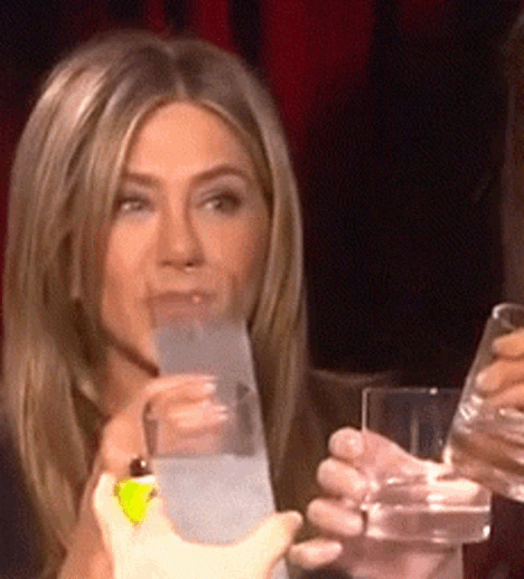 a woman is holding a glass of water in her right hand