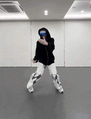 a person in a black hoodie and white pants is dancing in a dance studio