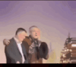 a blurry picture of two men standing next to each other in front of a building .