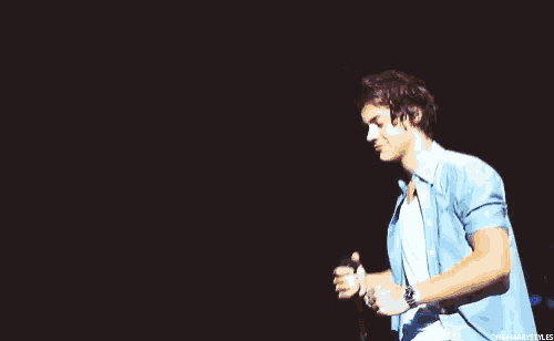 a man in a blue shirt and white shirt is holding a microphone in his hand