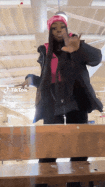 a woman with long hair is standing on a wooden bench in a room .