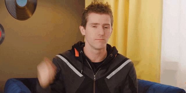a man sitting on a couch wearing a jacket that says ' dainese ' on it