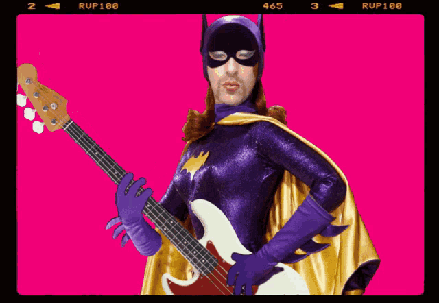 a man in a batgirl costume playing a bass guitar
