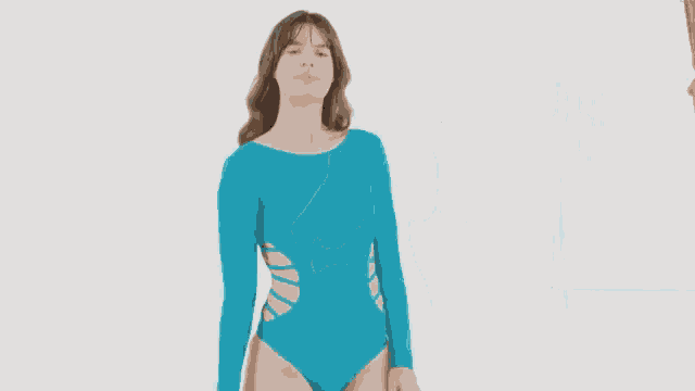 a woman is wearing a blue swimsuit with long sleeves and a cut out in the back .