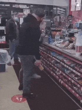 a man wearing a mask is standing in front of a shelf that says 74