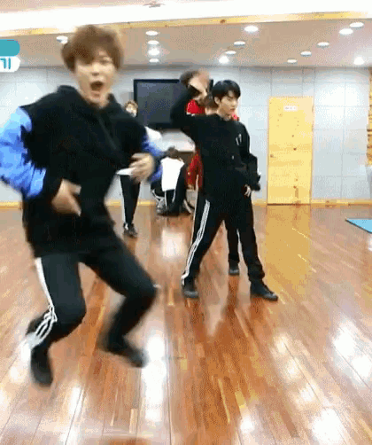 a group of young men are dancing on a wooden floor in a room .
