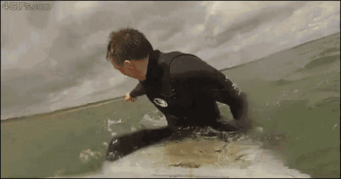 a man in a wet suit is riding a wave on a surfboard .