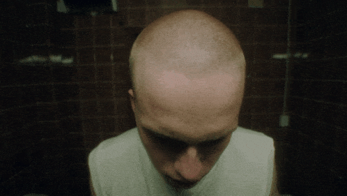 a man with a shaved head and a white shirt