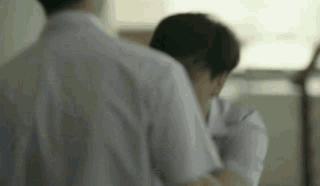 a man in a white shirt is hugging another man in a white shirt in a room .