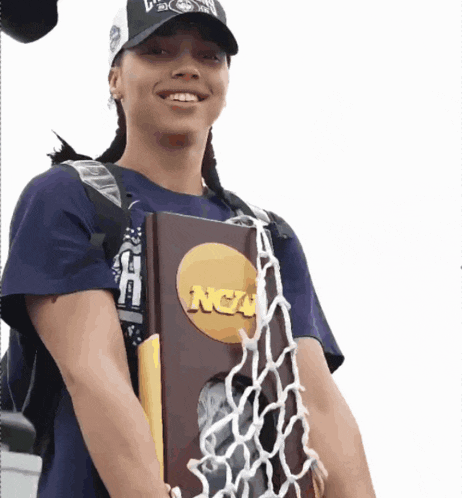 a woman holding a ncaa trophy and a net