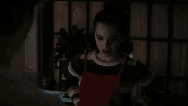 a young woman is standing in a dark room looking at a man .