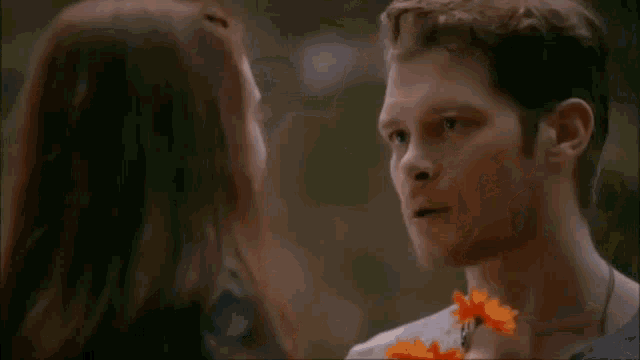a man and a little girl are looking at each other . the little girl has flowers in her hair .