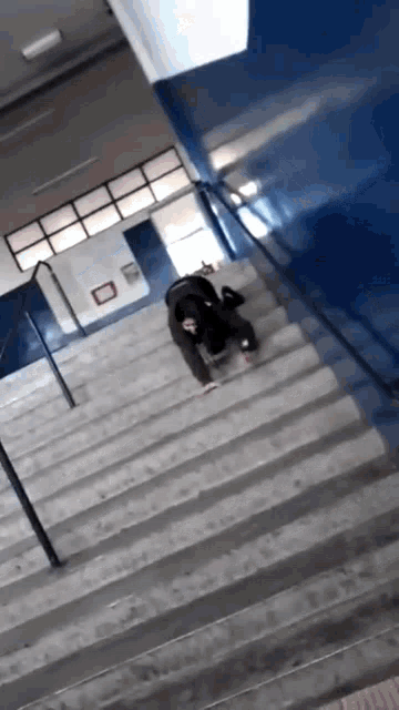 a person crawling up a set of stairs with a blue wall behind them