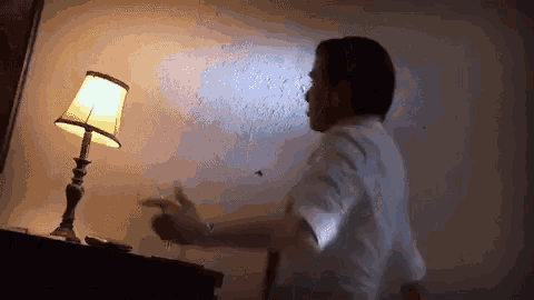 a man in a white shirt and tie is standing in front of a lamp .