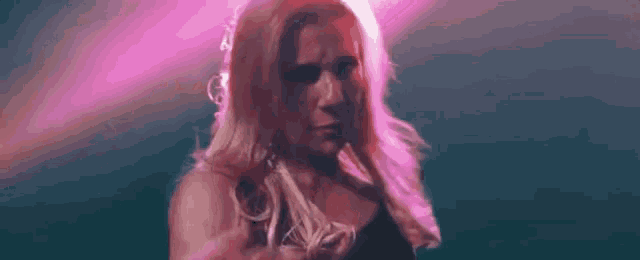 a woman with long red hair is standing in front of a pink light and looking at the camera .