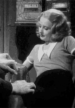 a woman is sitting in a chair with a man 's hand on her knee .