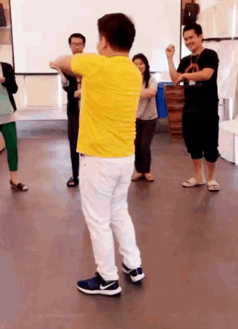 a man in a yellow shirt is dancing in a room