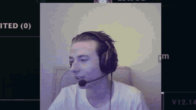 a man wearing headphones and a microphone is sitting in front of a screen that says v12.14