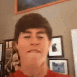a young boy is making a funny face in front of a wall of framed pictures .