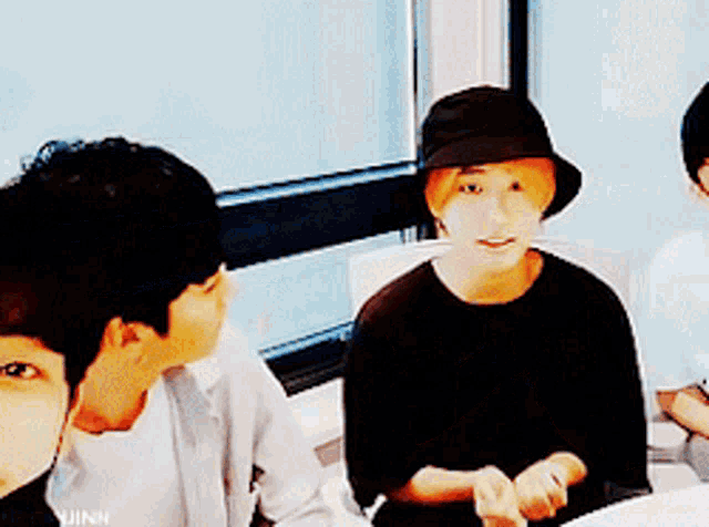 a man wearing a black hat is sitting next to another man .
