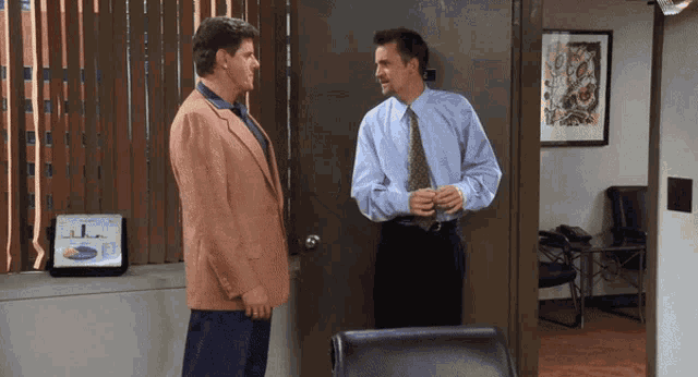 a man in a suit and tie talks to another man