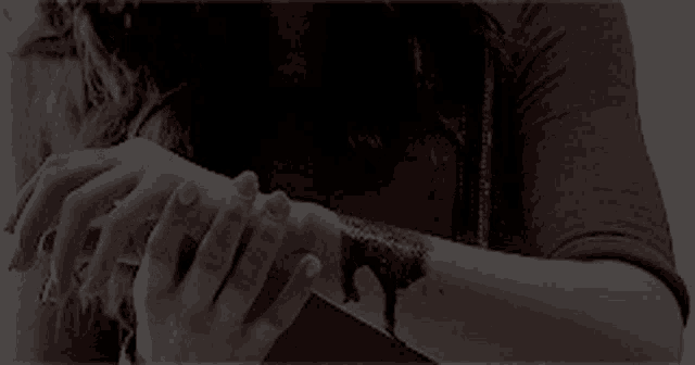 a woman is cutting her wrist with a knife in a black and white photo