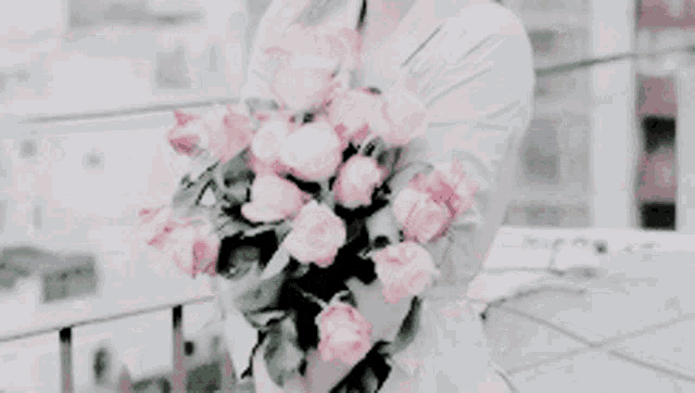 a woman holding a bouquet of pink roses in her hands