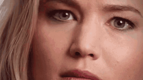 a close up of a woman 's face with blue eyes and a pink lip .