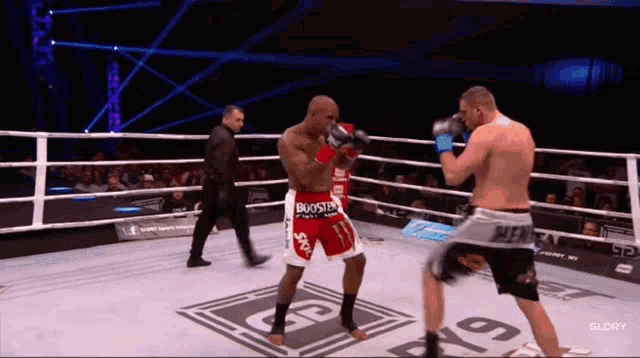 two boxers are fighting in a boxing ring and one of them is wearing red shorts that say booster