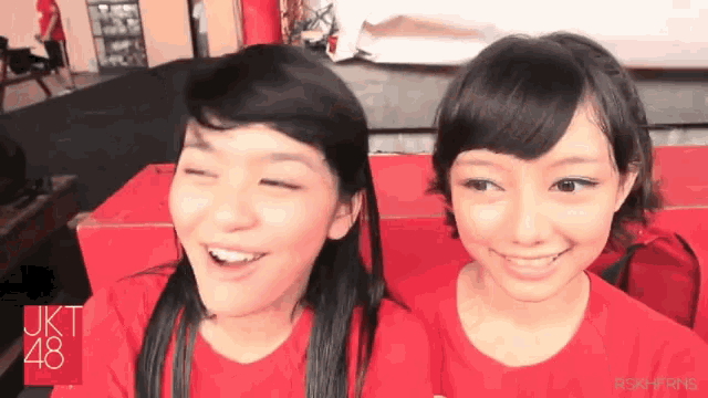 two girls wear red shirts that say okt 48