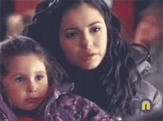 a woman and a little girl are looking at something with the letter u in the corner