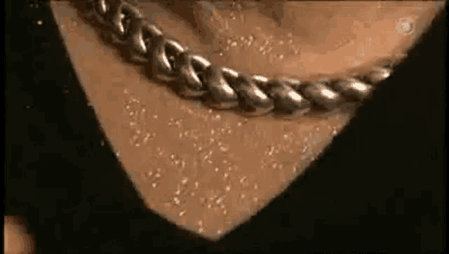 a close up of a person 's neck with a silver chain around it .