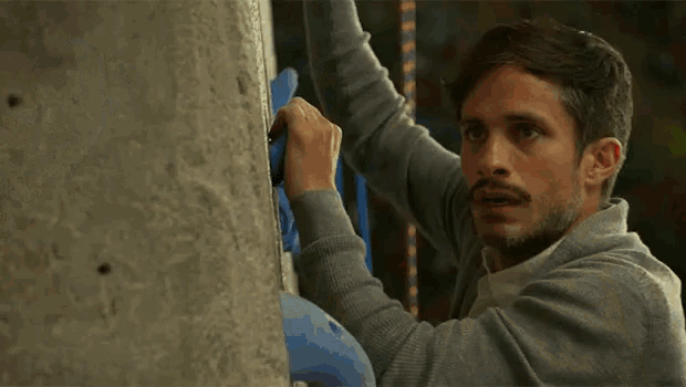 a person is climbing a rock wall with blue gloves