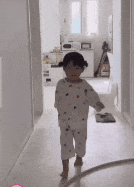 a little girl is walking down a hallway in a room .