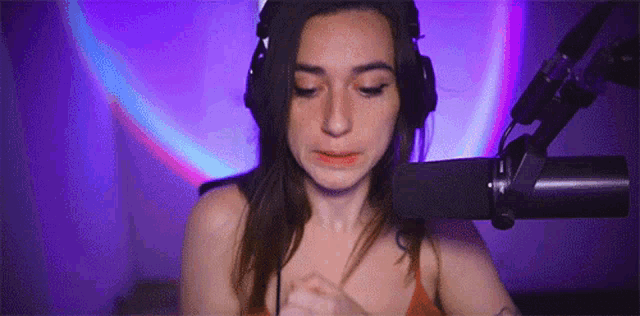 a woman wearing headphones is sitting in front of a microphone and crying .