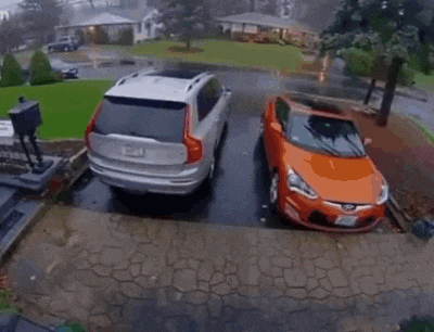 a canoe is leaning against a car parked in a driveway .