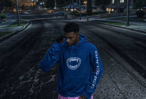 a man wearing a blue hoodie that says gangsta on the sleeve