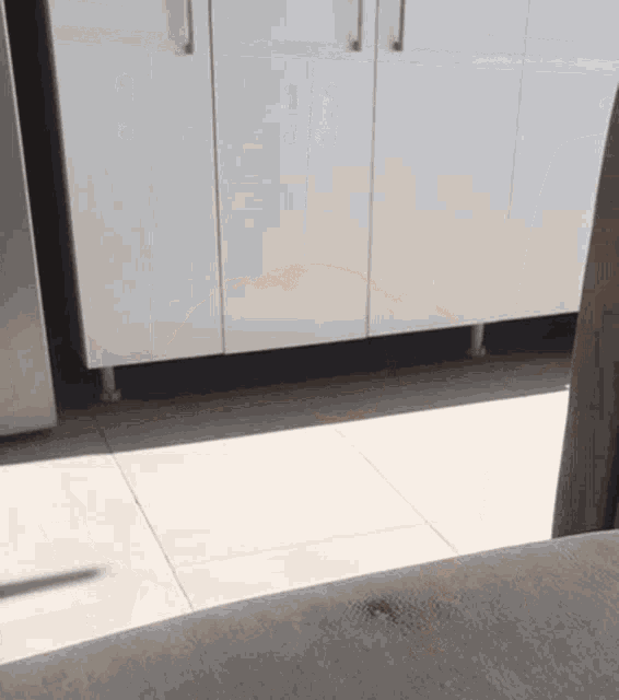 a kitchen with white cabinets and tile floors